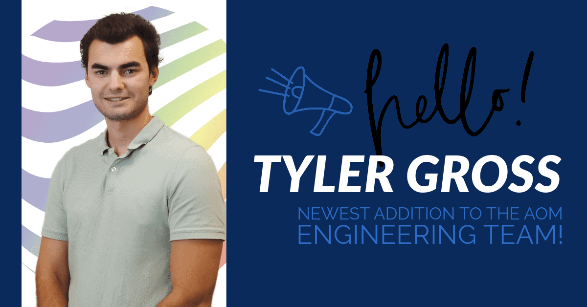 Photo of Tyler in front of the AOM rainbow hologram with the words, "hello! Tyler Gross newest addition to the AOM engineering team.