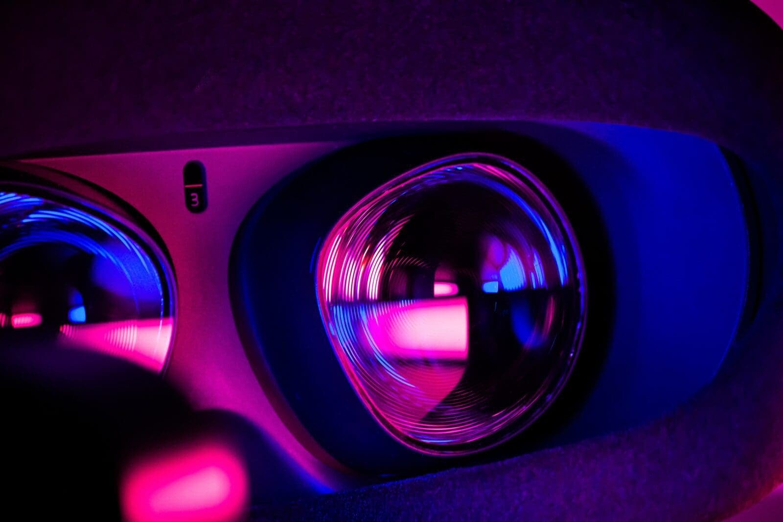 VR headset with pink and purple light glinting off the glass